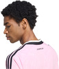 Ein Mann mit lockigem Haar trägt ein pinkes Trikot mit schwarzen Streifen.