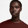 Porträt einer Frau mit kurzen Haaren und dunkler Haut, die ein dunkelrotes T-Shirt trägt.