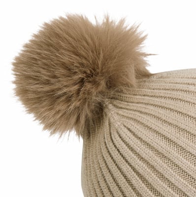 Eine beige Strickmütze mit braunem Pelzpompon.