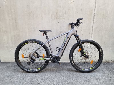 Graues Genesis Mountain E-Bike mit schwarzen Rädern und grünen Details. Graues Genesis Mountain E-Bike mit schwarzen Rädern und grünen Details.