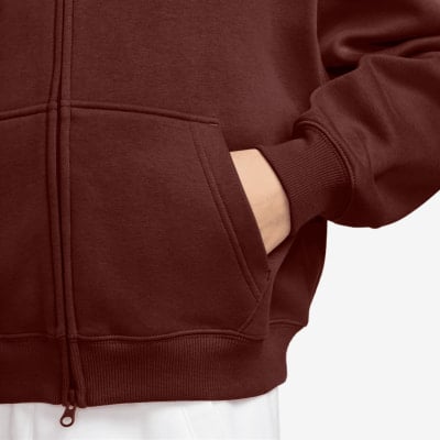 Nahaufnahme einer Hand in der Tasche eines dunkelroten Reißverschluss-Hoodies. Nahaufnahme einer Hand in der Tasche eines dunkelroten Reißverschluss-Hoodies.
