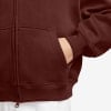 Nahaufnahme einer Hand in der Tasche eines dunkelroten Reißverschluss-Hoodies.