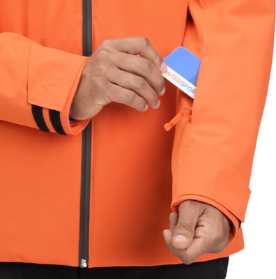 Ein Mann steckt eine Karte in eine Ärmeltasche einer orangefarbenen Jacke. Ein Mann steckt eine Karte in eine Ärmeltasche einer orangefarbenen Jacke.