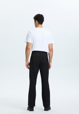 Ein Mann in schwarzen Hosen mit Schlitz und weißem T-Shirt steht rückwärts. Ein Mann in schwarzen Hosen mit Schlitz und weißem T-Shirt steht rückwärts.