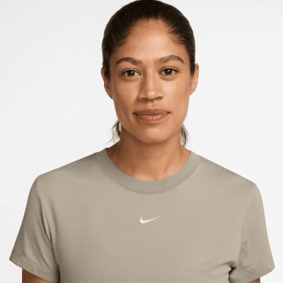 Eine Frau in einem beige T-Shirt mit Nike-Logo auf der Brust. Eine Frau in einem beige T-Shirt mit Nike-Logo auf der Brust.