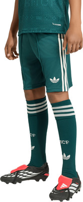 Kind in dunkelgrünem Fußballtrikot und Shorts mit weißen Streifen. Kind in dunkelgrünem Fußballtrikot und Shorts mit weißen Streifen.