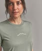 Eine Frau in einem grünen T-Shirt mit einem Berglogo und dem Schriftzug ORTOVOX.