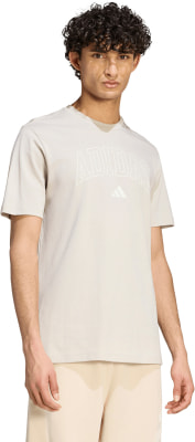 Ein Mann in einem beigefarbenen Adidas-T-Shirt und kurzen hellen Shorts. Ein Mann in einem beigefarbenen Adidas-T-Shirt und kurzen hellen Shorts.
