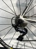Eine hintere Schaltwerk an einem weißen Rennrad mit schwarzen Speichen.