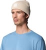 Mann mit Strickmütze und blauem T-Shirt vor weißem Hintergrund.