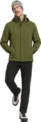 Ein Mann in einer grünen Jacke, schwarzer Hose und gestreifter Mütze steht vor weißem Hintergrund. Ein Mann in einer grünen Jacke, schwarzer Hose und gestreifter Mütze steht vor weißem Hintergrund.