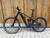 Ein schwarzes TREK E-Bike mit Federung steht vor einer Holzwand.