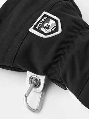 Schwarze Hestra-Handschuh mit Logo und Karabiner, Detail. Schwarze Hestra-Handschuh mit Logo und Karabiner, Detail.
