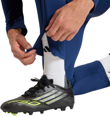 Mann schließt Reißverschluss an blauer Sporthose über Fußballschuh. Mann schließt Reißverschluss an blauer Sporthose über Fußballschuh.