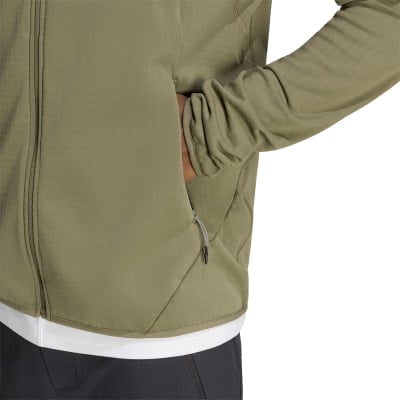 Ein Mann in einem grünen Hoodie steckt seine Hand in die Tasche.