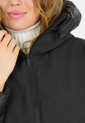 Detail einer schwarzen Damenjacke mit weißem Rollkragen und Kapuze. Detail einer schwarzen Damenjacke mit weißem Rollkragen und Kapuze.