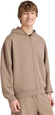 Ein junger Mann mit braunen Haaren lächelt in einem beigefarbenen Reißverschluss-Hoodie. Ein junger Mann mit braunen Haaren lächelt in einem beigefarbenen Reißverschluss-Hoodie.