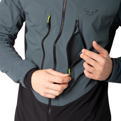 Ein Mann öffnet eine Netz-Tasche an einer Jacke mit einem Neon-Reißverschluss.