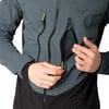 Ein Mann öffnet eine Netz-Tasche an einer Jacke mit einem Neon-Reißverschluss.