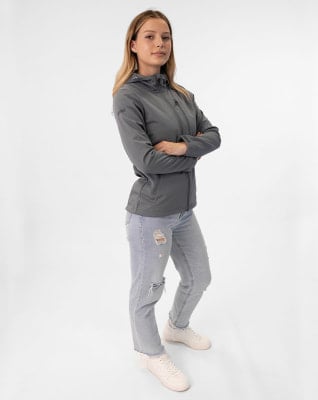 Eine Frau in einer grauen Jacke und zerrissener Jeans steht mit verschränkten Armen. Eine Frau in einer grauen Jacke und zerrissener Jeans steht mit verschränkten Armen.
