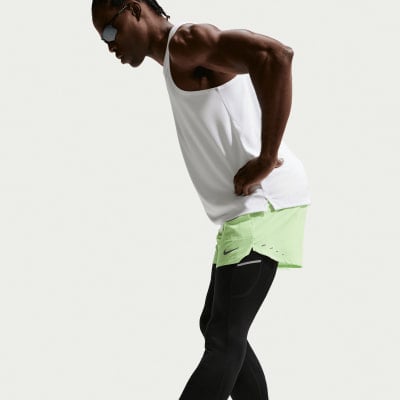 Ein Mann in einem weißen Tanktop und hellgrünen Shorts mit schwarzen Leggings.