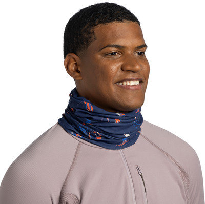 Mann in einem Halstuch mit Skifahrermotiv und einem dunkelvioletten Pullover mit Reißverschluss.