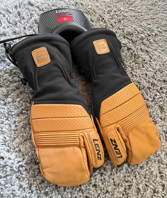 Schwarze und braune Skihandschuhe mit Lenz-Heizung auf Teppich. Schwarze und braune Skihandschuhe mit Lenz-Heizung auf Teppich.