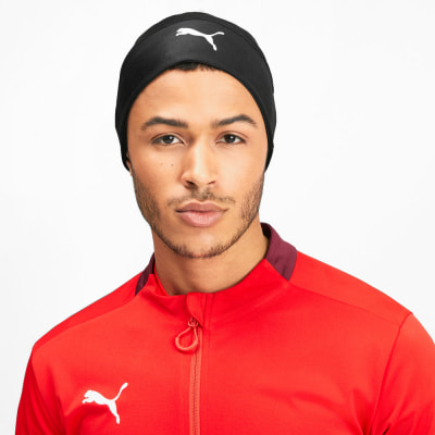 Ein Mann in einer schwarzen Mütze mit Puma-Logo und roter Jacke.