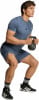 Ein Mann in blauem Shirt und Shorts macht Kniebeugen mit Kettlebell.