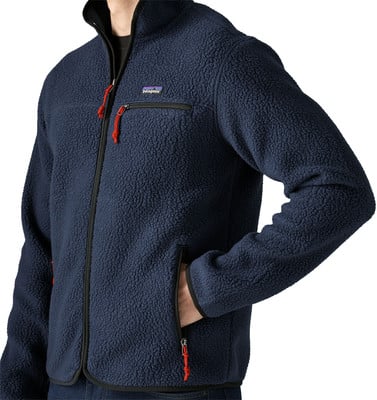 Ein Mann trägt eine dunkelblaue Fleecejacke mit roten Details.
