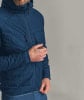 Ein Mann in einer blauen Daunenjacke mit Kapuze und gestepptem Muster.