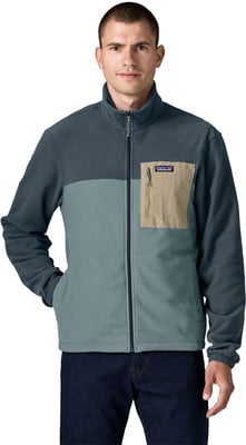 Ein Mann in einer dunkelblauen Fleecejacke mit einer beige Tasche und dunkelblauen Jeans. Ein Mann in einer dunkelblauen Fleecejacke mit einer beige Tasche und dunkelblauen Jeans.
