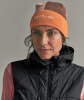Eine Frau in einer orange-braunen Mütze und einer schwarzen Weste blickt zur Seite.