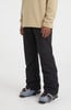 Ein Mann in schwarzer Skihose und beige Pullover mit Skischuhen.