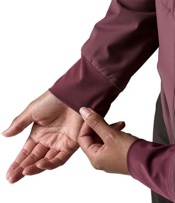 Detail einer Hand und eines Ärmels eines dunkelweinroten Kleidungsstücks auf weißem Grund. Detail einer Hand und eines Ärmels eines dunkelweinroten Kleidungsstücks auf weißem Grund.