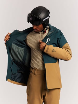 Ein Mann in einer Skijacke und einem Helm betrachtet die Innentaschen der Jacke. Ein Mann in einer Skijacke und einem Helm betrachtet die Innentaschen der Jacke.