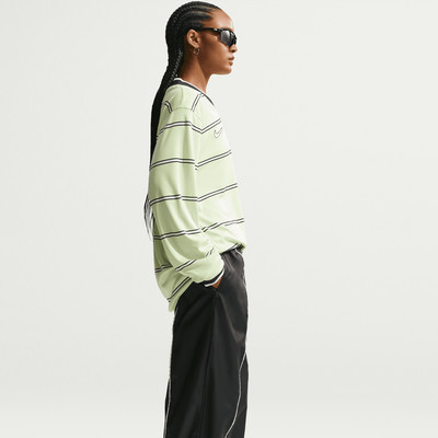 Ein Model in einem gestreiften Oberteil und einer schwarzen Hose mit dezentem Nike-Logo.