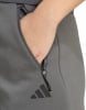 Hand in der Tasche einer grauen Adidas Hose mit Reißverschluss.