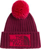 Eine rote Strickmütze mit Bommel und The North Face Logo.