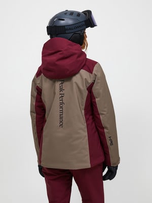 Rückansicht einer Skifahrerin in einer Peak Performance Jacke und einem Salomon Helm. Rückansicht einer Skifahrerin in einer Peak Performance Jacke und einem Salomon Helm.