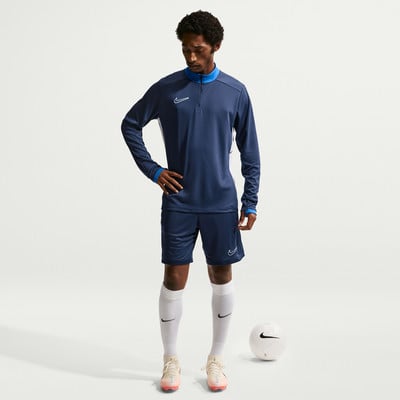 Ein Mann im dunkelblauen Nike-Trainingsanzug steht neben einem Ball. Ein Mann im dunkelblauen Nike-Trainingsanzug steht neben einem Ball.