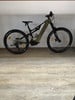 Ein olivgrünes Genesis E-Mountainbike steht auf einem Holzboden.