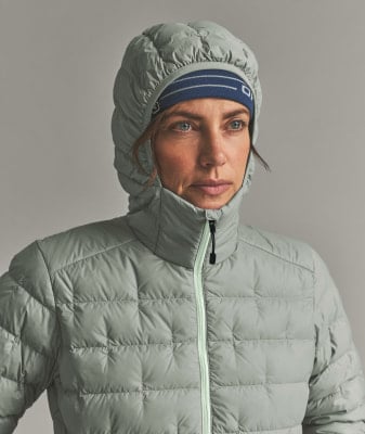 Eine Frau in einer Daunenjacke und einer Mütze mit blauem Streifenband. Eine Frau in einer Daunenjacke und einer Mütze mit blauem Streifenband.