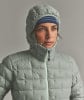 Eine Frau in einer Daunenjacke und einer Mütze mit blauem Streifenband.