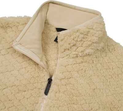 Detail des cremefarbenen Fleecekragens und Reißverschlusses einer Jacke.