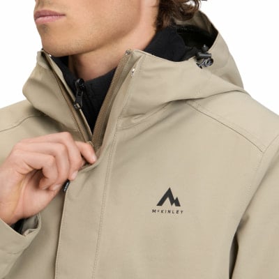 Ein Mann schließt eine beige Jacke mit McKinley-Logo auf der Brust. Ein Mann schließt eine beige Jacke mit McKinley-Logo auf der Brust.