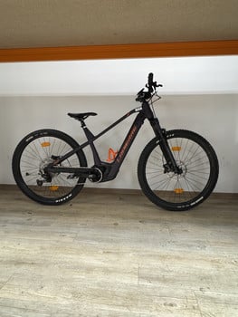 Ein schwarzes Lapierre E-Bike mit orangefarbenen Details auf Holzboden.