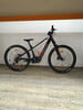 Ein schwarzes Lapierre E-Bike mit orangefarbenen Details auf Holzboden.