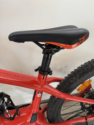 Ein rotes Mountainbike mit schwarzem Sattel und orangen Details, Nahaufnahme. Ein rotes Mountainbike mit schwarzem Sattel und orangen Details, Nahaufnahme.
