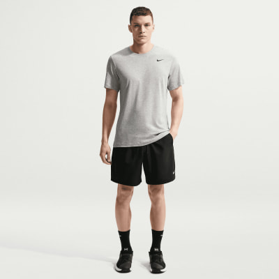 Ein Mann in einem grauen Nike-T-Shirt und schwarzer Hose steht in einer Pose.